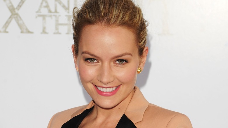 Sporting a full-face glam, Becki Newton flashes a broad, toothy smile.