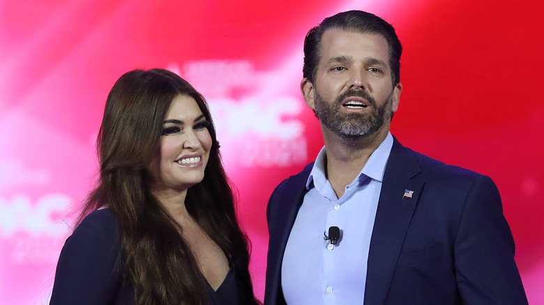 Donald Trump Jr. and Kimberly Guilfoyle smiling at a 2021 politcal rally