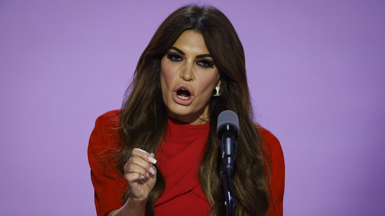 Kimberly Guilfoyle speaking in front of microphone with her hand raised