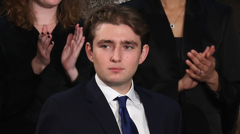 Barron Trump attending the 2026 State of the Union address in a black suit with a navy tie