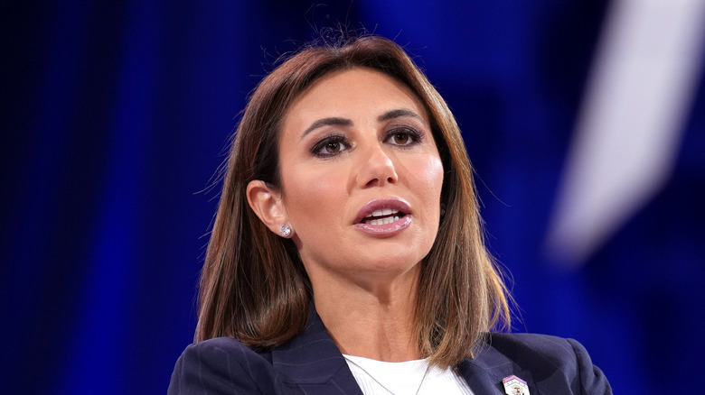 Alina Habba speaking in a navy blazer with a white top underneath