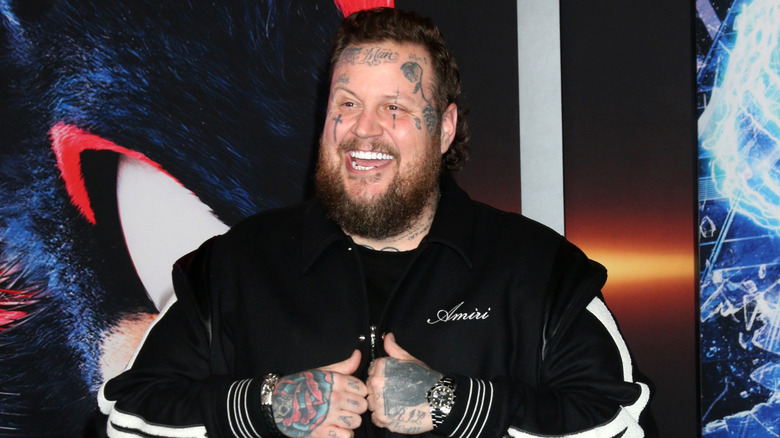 Jelly Roll smiling while holding his jacket